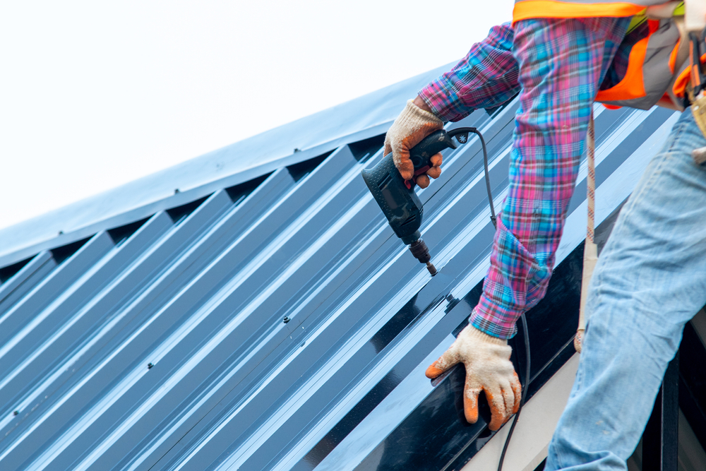 Roofer,with,electric,drill,used,on,new,roofs,with,metal