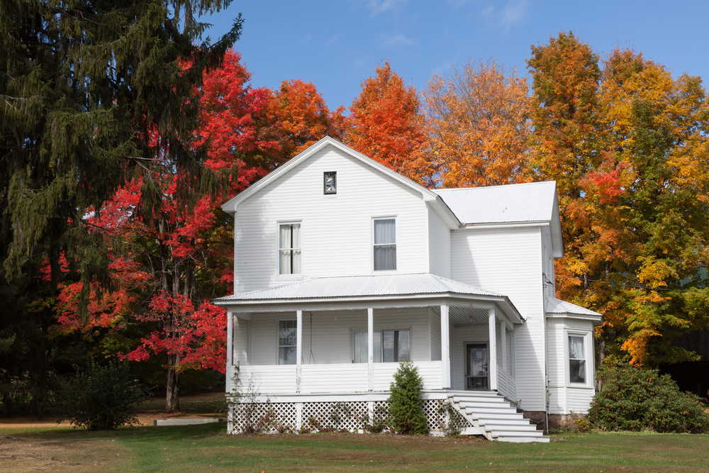 White Maryland home with metal roof surrounded by colorful fall trees